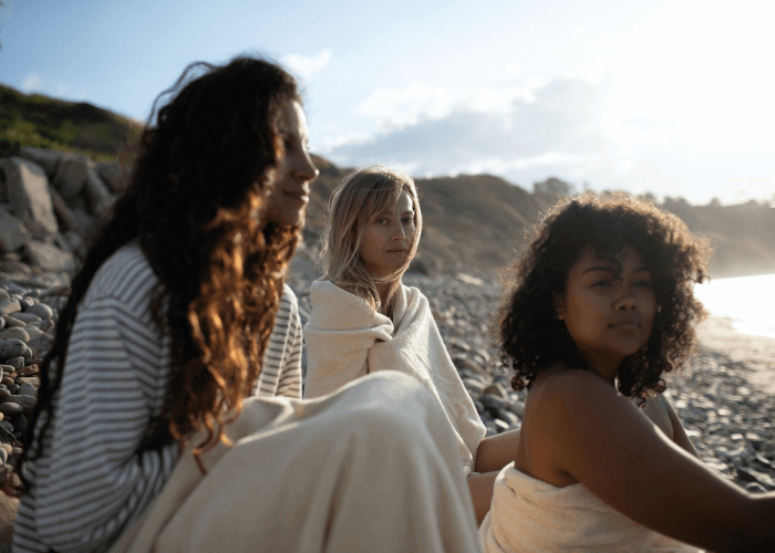 Three Women Sitting on a Beach Dressed in California Cloth Foundry Clothing