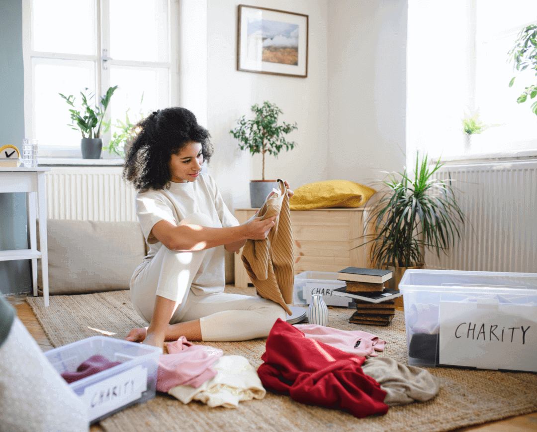 A young woman sorting her wardrobe and giving items to charity