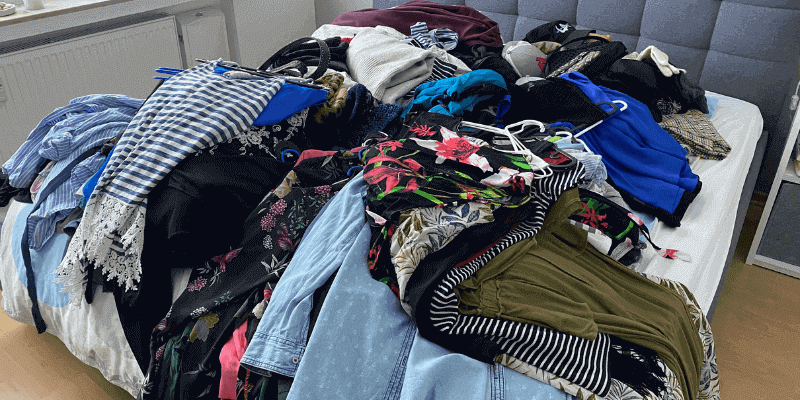 Minimalistisch Wohnen Vorher: Ein Haufen von Kleidung auf einem Bett.